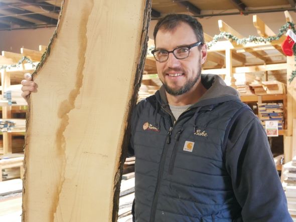 Lucas Jenson holds a live edge slab of wood