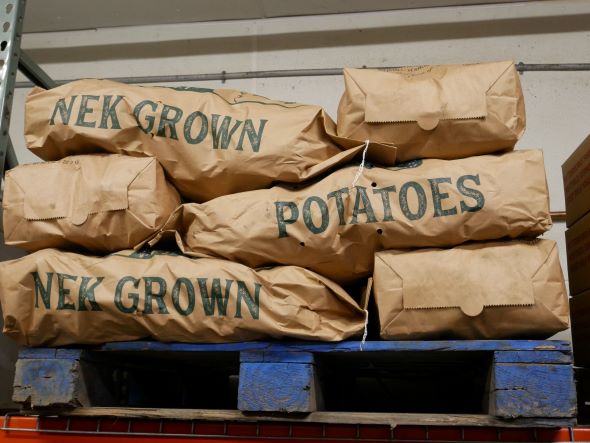 Bags of potatoes on a shelf that say "NEK Grown Potatoes"