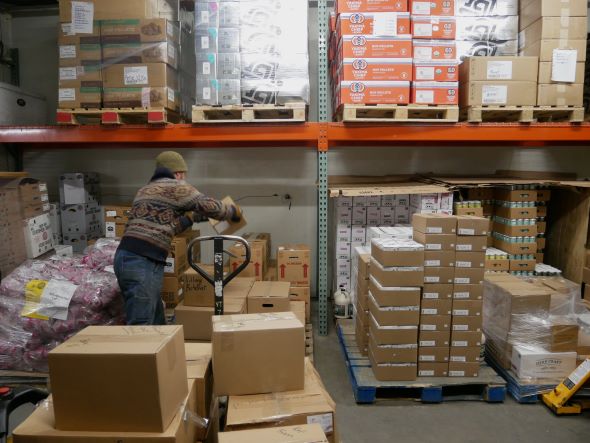 A person loads pallets of food and beverage products in a warehouse