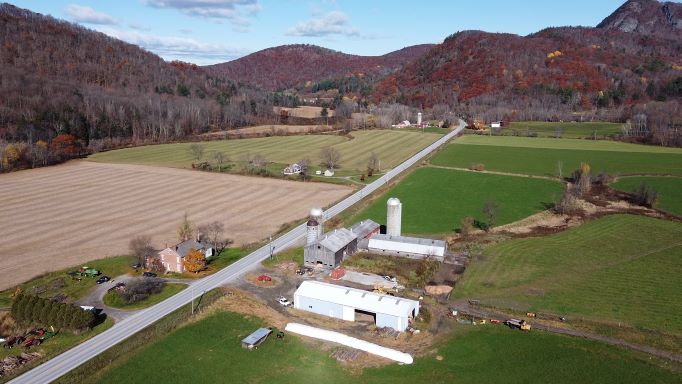 aerial image of a farm with a mountain in the background, in the fall