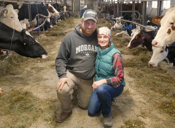 Chet and Renee Baker kneel in the barn surrounded by cows in their stalls
