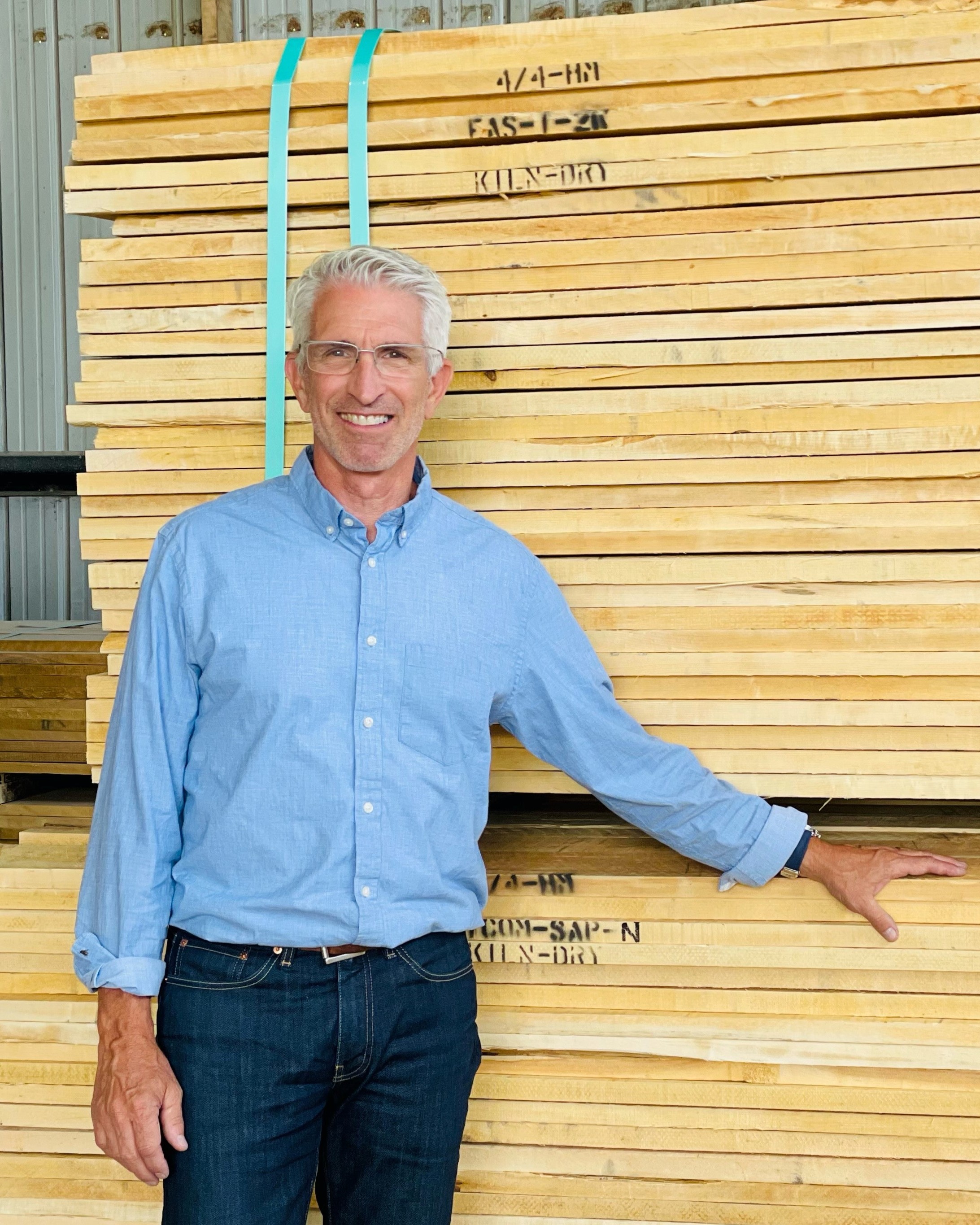 Chris Castano stands in front of stacked lumber
