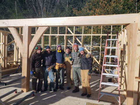 Image of a group of people posing in front of a new house/barn structure