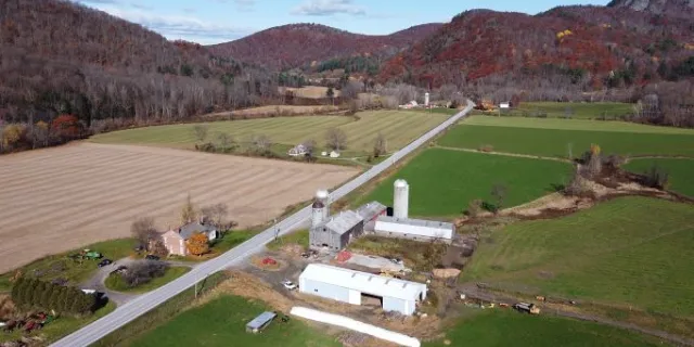 aerial view of a farm in a valley fall with mountains in the background