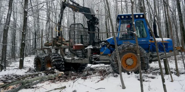 Forwarder moving logs in the winter woods