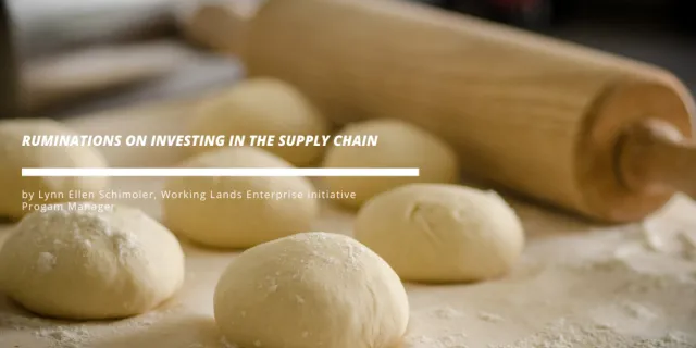 Several balls of dough on a floured surface with a rolling pin in the background.