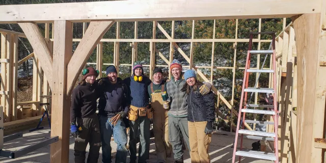 Image of a group of people posing in front of a new house/barn structure