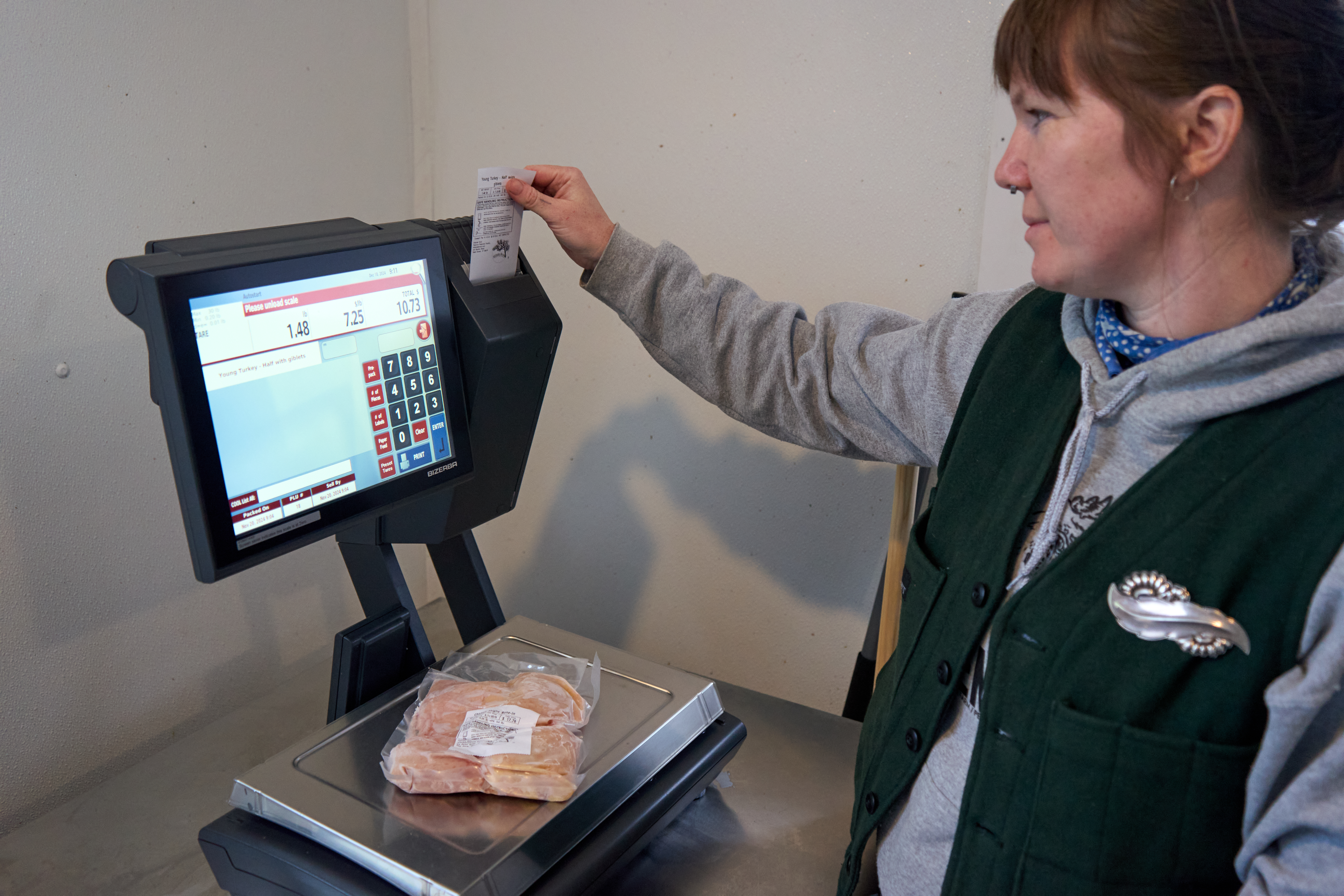 A young woman weighs a package of chicken on a scale