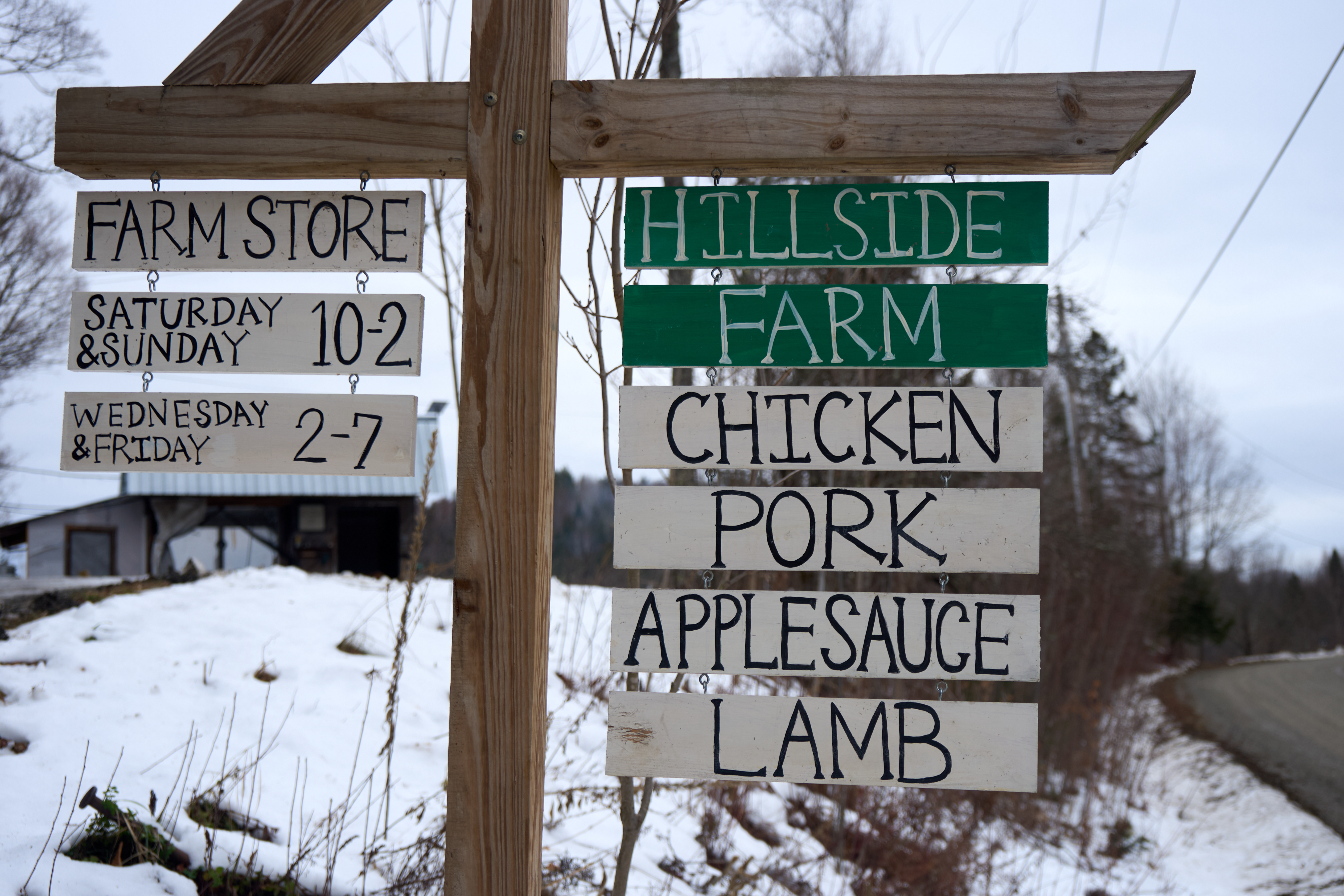 A wooden farm store sign advertising farm products
