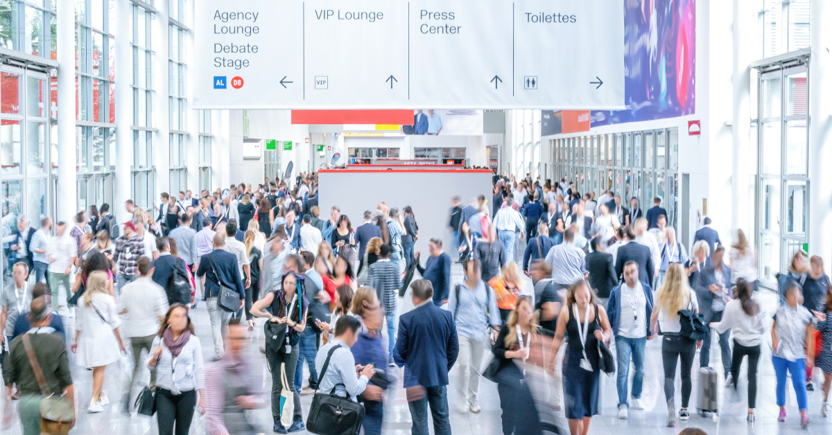 Stock image of a trade show hall filled with people and signs